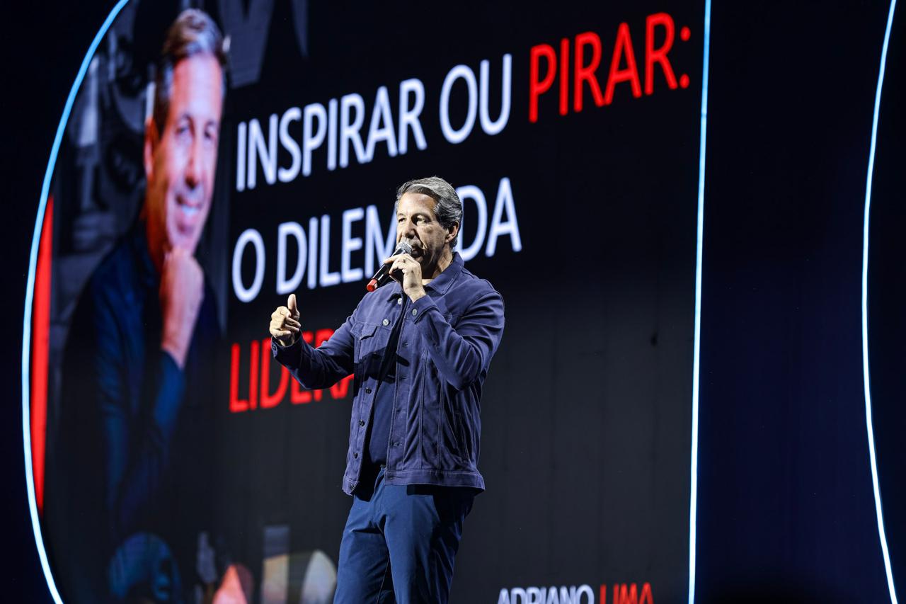 Adriano Lima palestrando à frente de um telão com a frase “Inspirar ou pirar: o dilema da liderança”